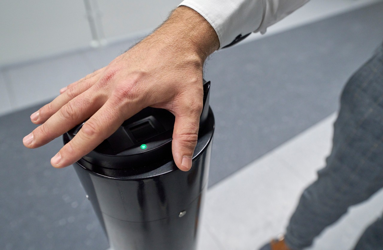 Er legt seine Hand auf den Handvenenscanner.