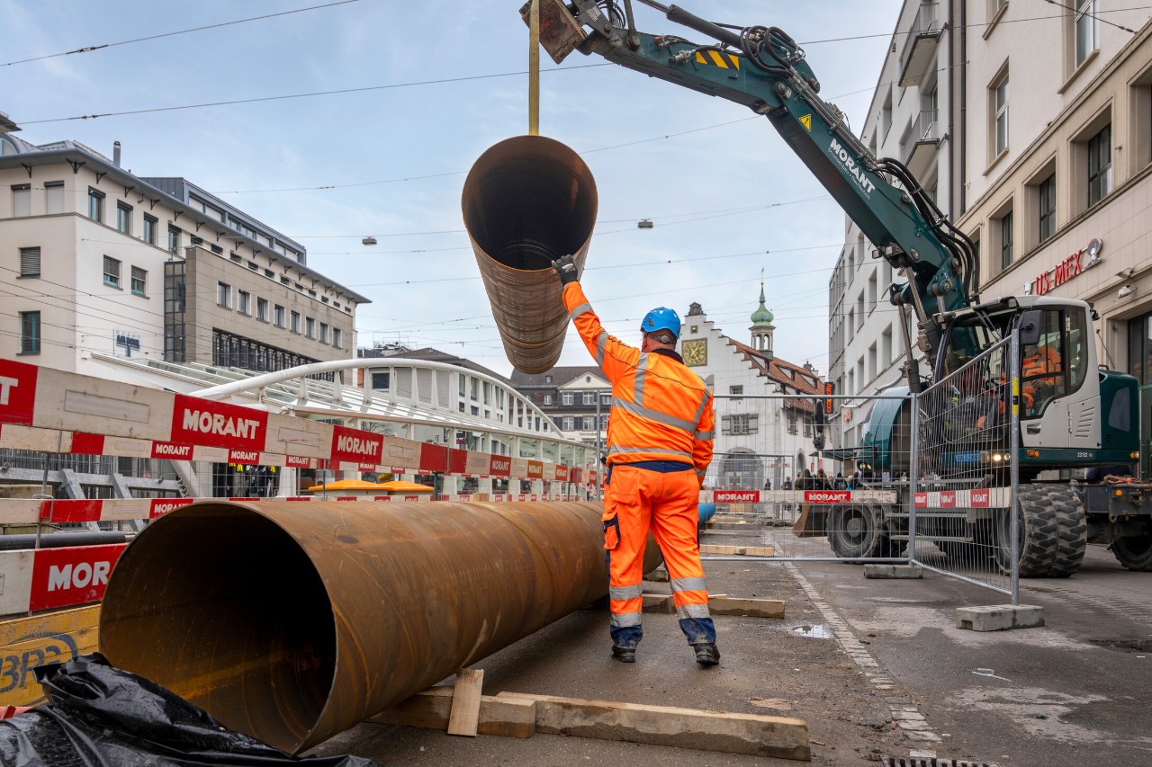 In die Baugrube am Marktplatz wird ein etwas rostig ausschauendes Rohr verlegt. Dieses dient als Schutz für die Wasserleitung. 