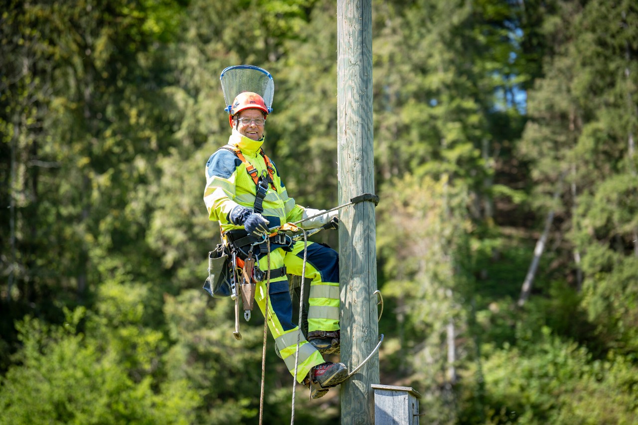 Gesichert mit einem Gurt, den er um den Mast gelegt hat, steigt er routiniert hinauf.