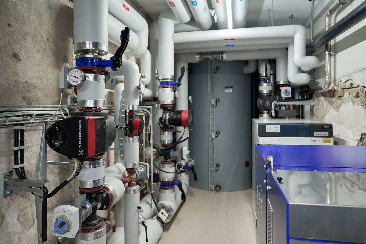 Im Vordergrund sind die zwei BHKW zu sehen, dahinter befindet sich der Gaskessel, der Wärmespeicher ist zuhinderst und links befindet sich die Wärmeverteilung.